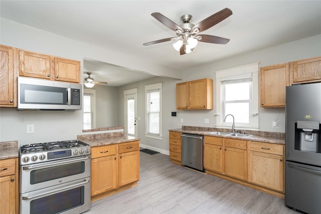 2124 E 23rd St, Des Moines, IA 50317 - kitchen with stainless steel appliances, a ceiling fan, light wood-style floors, and healthy amount of natural light
