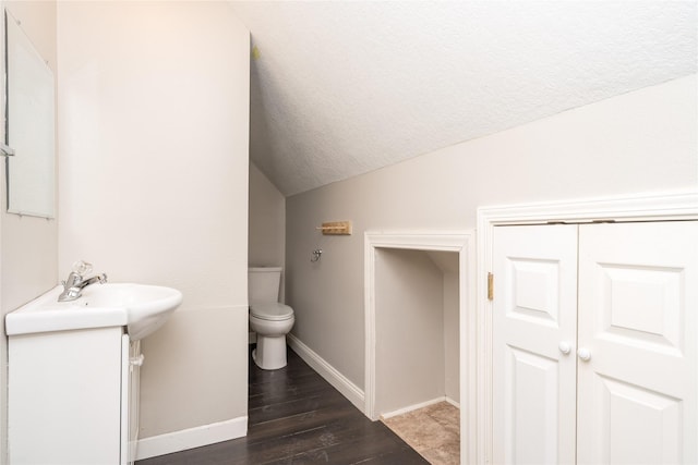 2124 E 23rd St, Des Moines, IA 50317 - half bath with vaulted ceiling, wood finished floors, and a textured ceiling