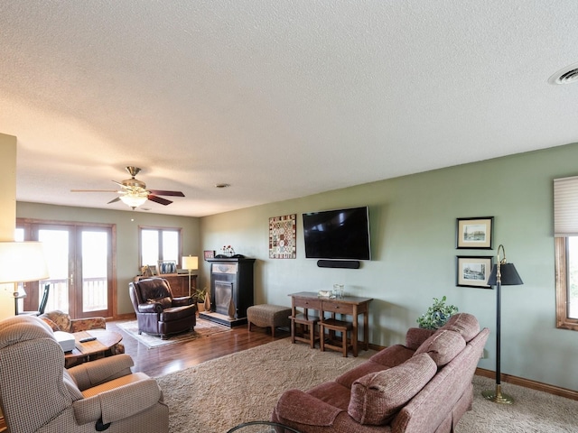 1246 N 75th Ave W, Newton, IA 50208 - living area with a textured ceiling, a fireplace, a ceiling fan, and wood finished floors