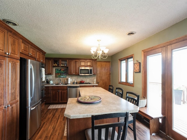 1246 N 75th Ave W, Newton, IA 50208 - kitchen with stainless steel appliances, light countertops, dark wood finished floors, a chandelier, and a textured ceiling