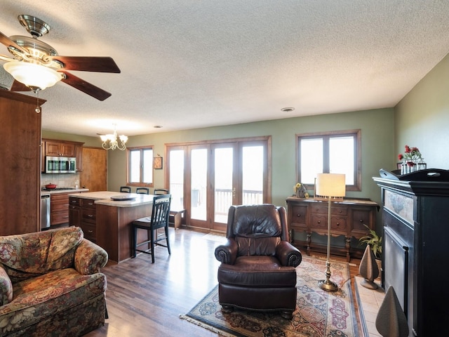 1246 N 75th Ave W, Newton, IA 50208 - living area featuring a textured ceiling, a chandelier, ceiling fan, and light wood-style floors