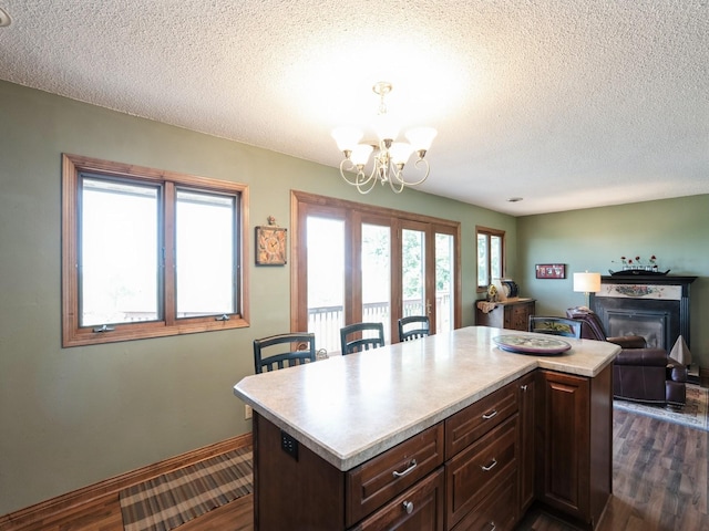 1246 N 75th Ave W, Newton, IA 50208 - kitchen with a chandelier, a textured ceiling, dark wood-style flooring, light countertops, and a glass covered fireplace