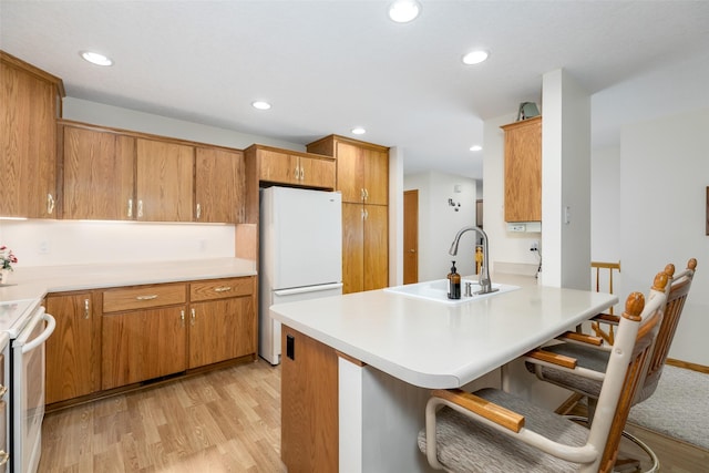 1412 Court St, Adel, IA 50003 - kitchen featuring white appliances, light wood-style flooring, a breakfast bar, a peninsula, and brown cabinets