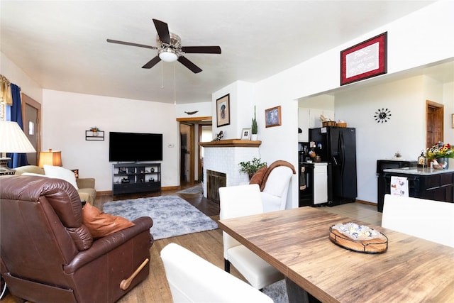 3851 E 25th St, Des Moines, IA 50317 - living area featuring a ceiling fan, a brick fireplace, and light wood-style floors