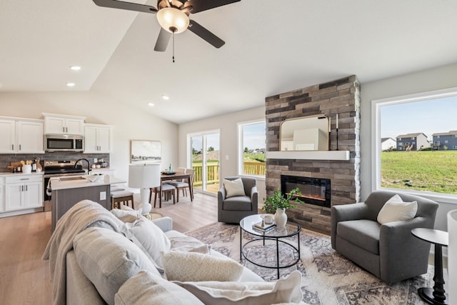 4422 NW Olivia Ln, Ankeny, IA 50023 - living area featuring light wood-style flooring, vaulted ceiling, ceiling fan, a large fireplace, and recessed lighting
