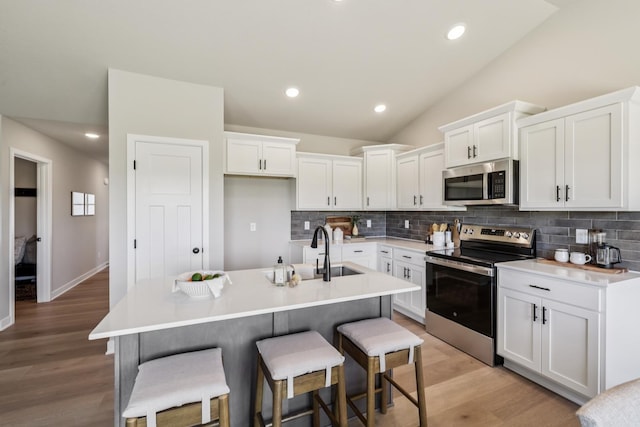 4422 NW Olivia Ln, Ankeny, IA 50023 - kitchen with appliances with stainless steel finishes, decorative backsplash, lofted ceiling, white cabinetry, and a breakfast bar area