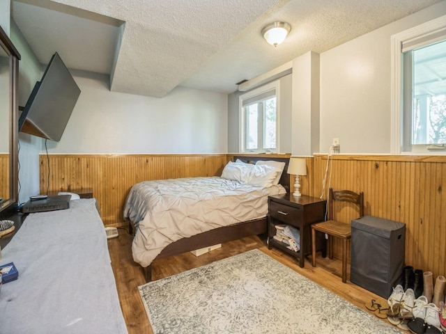 1907 Thornton Ct, Des Moines, IA 50320 - bedroom featuring a wainscoted wall, a textured ceiling, wood finished floors, and wooden walls