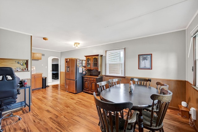 228 Hillside Ave, West Des Moines, IA 50265 - dining area featuring crown molding, arched walkways, wainscoting, light wood-style flooring, and wooden walls
