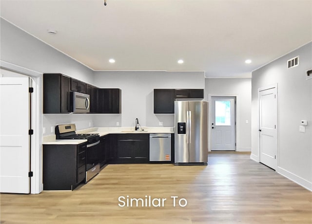 309 W Cherry St, Ogden, IA 50212 - kitchen featuring appliances with stainless steel finishes, light wood finished floors, light countertops, dark cabinetry, and recessed lighting