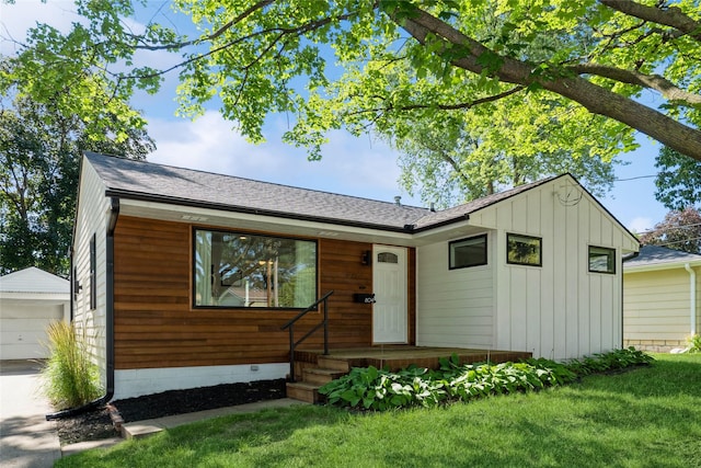 804 24th St, West Des Moines, IA 50265 - view of front of property with an outbuilding, a front yard, a shingled roof, and board and batten siding