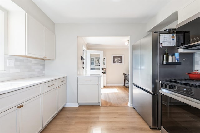 804 24th St, West Des Moines, IA 50265 - kitchen featuring stainless steel appliances, light wood finished floors, tasteful backsplash, white cabinets, and light countertops