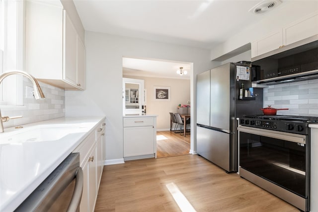 804 24th St, West Des Moines, IA 50265 - kitchen featuring appliances with stainless steel finishes, white cabinets, backsplash, light wood finished floors, and light countertops