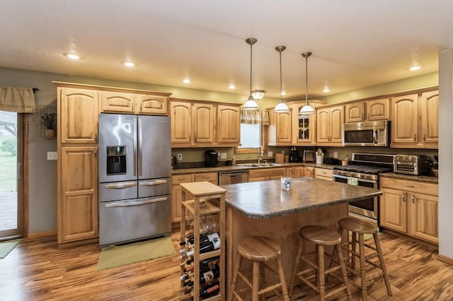 308 S 3rd St, Milo, IA 50166 - kitchen featuring appliances with stainless steel finishes, a breakfast bar, wood finished floors, dark countertops, and recessed lighting
