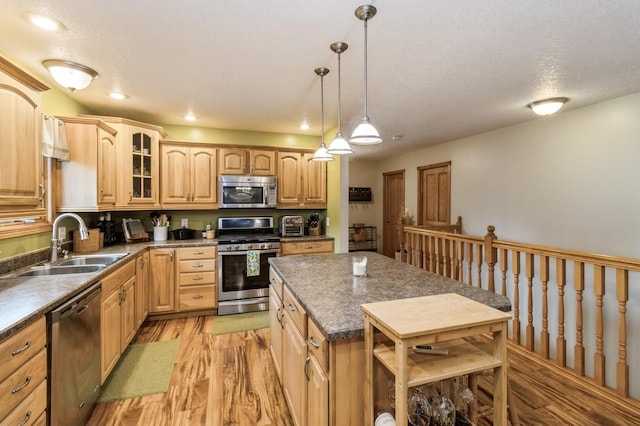 308 S 3rd St, Milo, IA 50166 - kitchen with stainless steel appliances, light wood finished floors, dark countertops, glass insert cabinets, and a textured ceiling