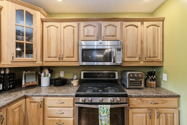 308 S 3rd St, Milo, IA 50166 - kitchen with stainless steel appliances, glass insert cabinets, light brown cabinets, and dark countertops
