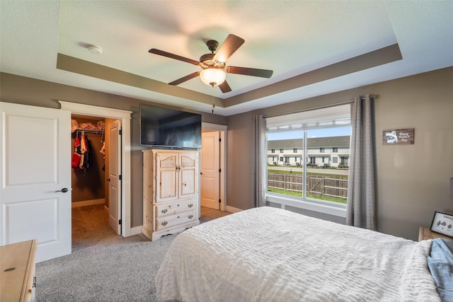 716 James St NE, Bondurant, IA 50035 - carpeted bedroom featuring a walk in closet, a raised ceiling, a closet, and a ceiling fan