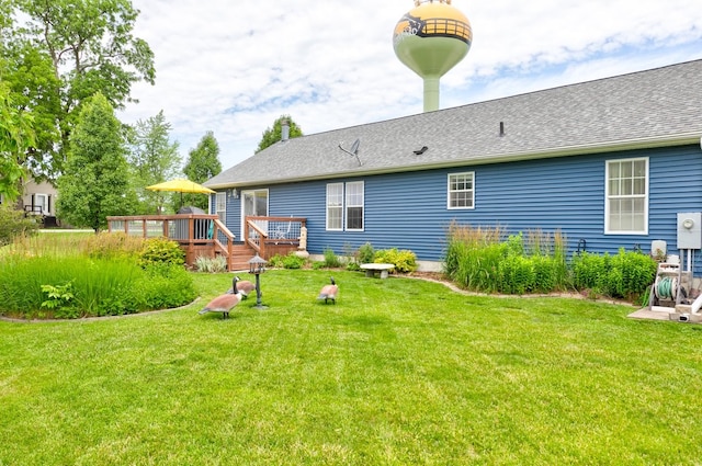201 E 1st St, Woodward, IA 50276 - rear view of house with a wooden deck, a yard, and roof with shingles