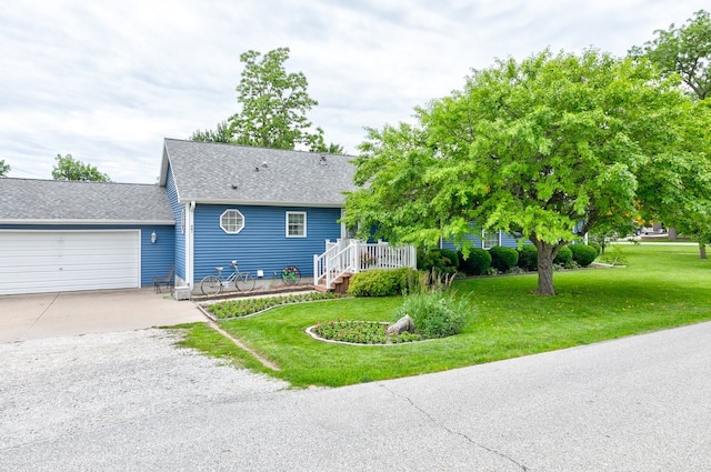 201 E 1st St, Woodward, IA 50276 - view of front facade featuring driveway, a garage, a front lawn, a shingled roof, and a wooden deck