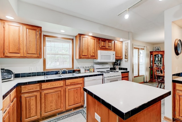 201 E 1st St, Woodward, IA 50276 - kitchen with white appliances, track lighting, recessed lighting, brown cabinets, and a kitchen island