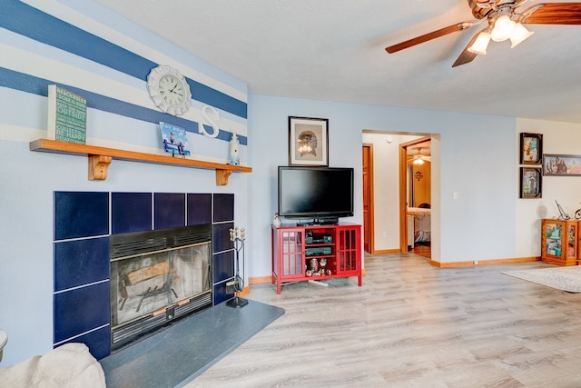 201 E 1st St, Woodward, IA 50276 - living area featuring a tiled fireplace, ceiling fan, and wood finished floors