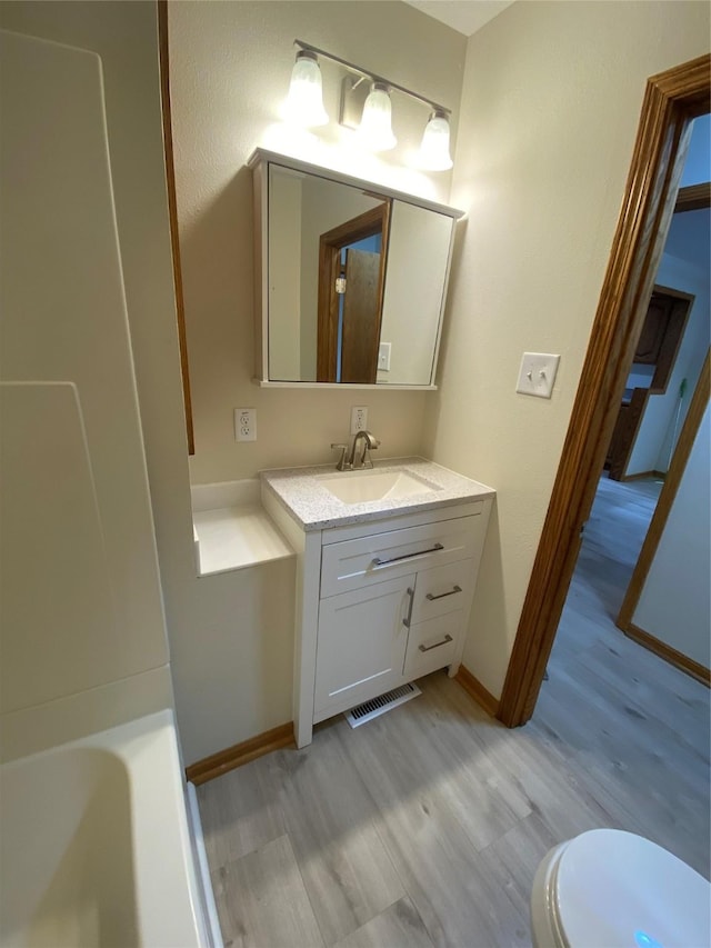 2615 59th St, Des Moines, IA 50322 - bathroom featuring wood finished floors, vanity, and a tub