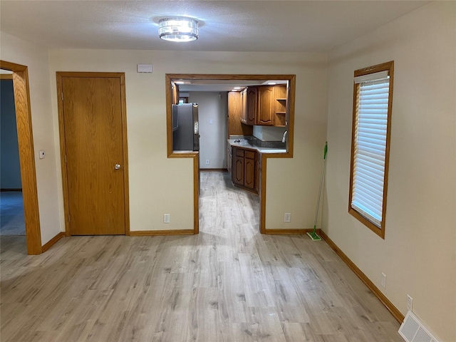 2615 59th St, Des Moines, IA 50322 - kitchen with freestanding refrigerator, light wood finished floors, brown cabinetry, and light countertops