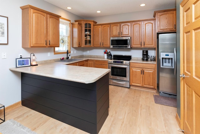 705 Patterson Dr, Carlisle, IA 50047 - kitchen with stainless steel appliances, light wood-type flooring, a peninsula, light countertops, and glass insert cabinets