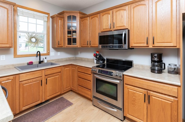 705 Patterson Dr, Carlisle, IA 50047 - kitchen featuring stainless steel appliances, light wood-type flooring, light countertops, and glass insert cabinets