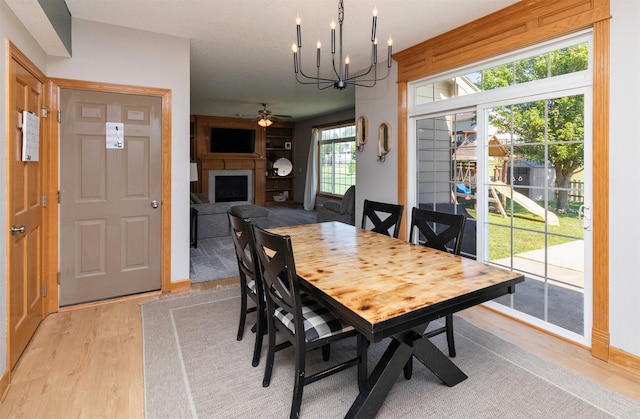 705 Patterson Dr, Carlisle, IA 50047 - dining room with a fireplace, light wood-type flooring, a chandelier, and a ceiling fan