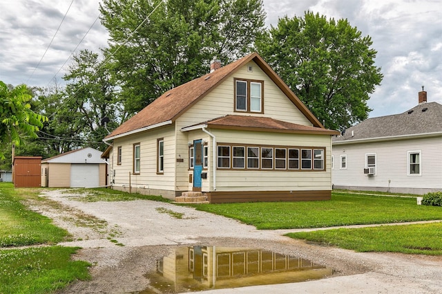 1442 Lucas Ave, Chariton, IA 50049 - view of front of property featuring an outdoor structure, driveway, a detached garage, a front yard, and a shingled roof