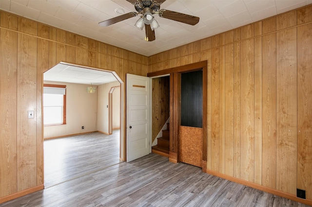 1442 Lucas Ave, Chariton, IA 50049 - spare room featuring wooden walls, wood finished floors, stairs, a ceiling fan, and arched walkways