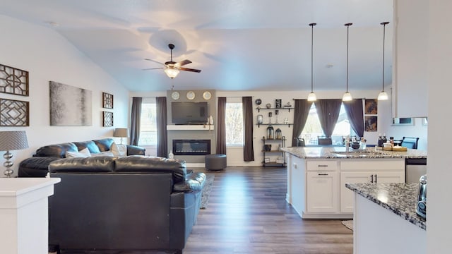 5453 Rowling Dr, Ames, IA 50014 - living room with dark wood-style floors, lofted ceiling, a ceiling fan, and a glass covered fireplace