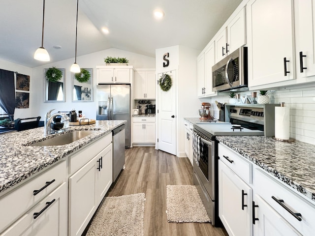 5453 Rowling Dr, Ames, IA 50014 - kitchen featuring stainless steel appliances, white cabinets, lofted ceiling, light stone counters, and light wood finished floors