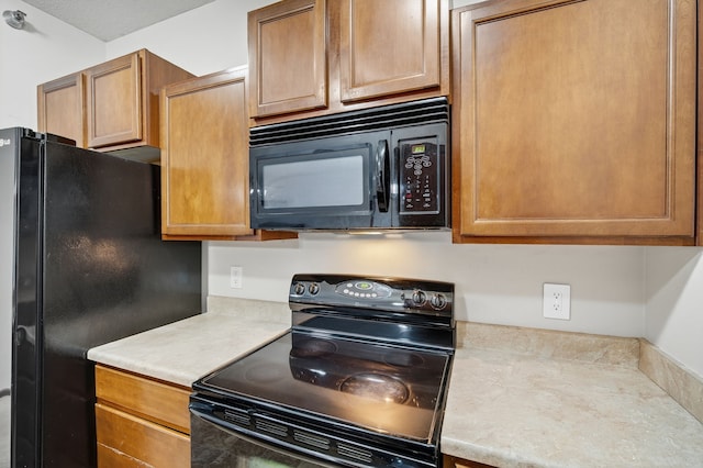 10320 Norfolk Dr Unit 7, Johnston, IA 50131 - kitchen with black appliances, light countertops, and brown cabinetry