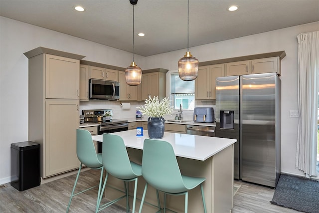 16621 Goodman Dr, Urbandale, IA 50323 - kitchen with appliances with stainless steel finishes, tasteful backsplash, light wood-type flooring, a center island, and light countertops