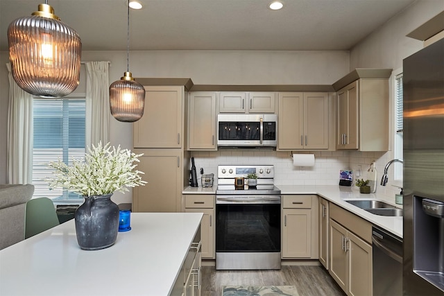 16621 Goodman Dr, Urbandale, IA 50323 - kitchen with appliances with stainless steel finishes, light countertops, light wood finished floors, tasteful backsplash, and pendant lighting