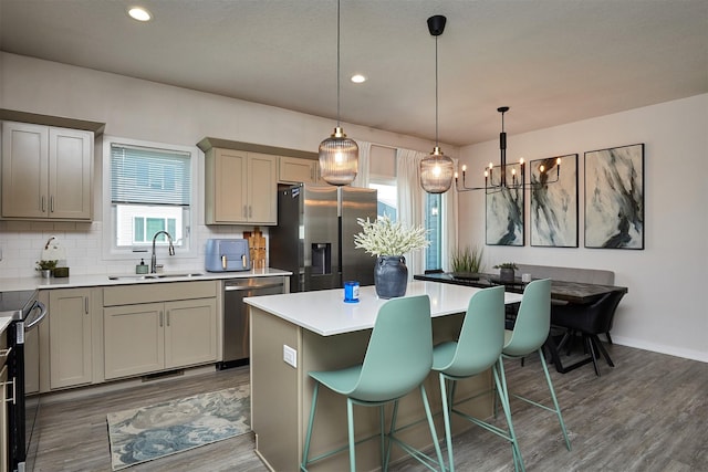 16621 Goodman Dr, Urbandale, IA 50323 - kitchen with stainless steel appliances, wood finished floors, a kitchen breakfast bar, tasteful backsplash, and recessed lighting