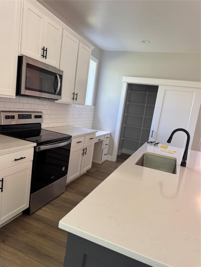 10009 Powell Ave, Johnston, IA 50131 - kitchen with appliances with stainless steel finishes, backsplash, white cabinetry, and dark wood-style floors