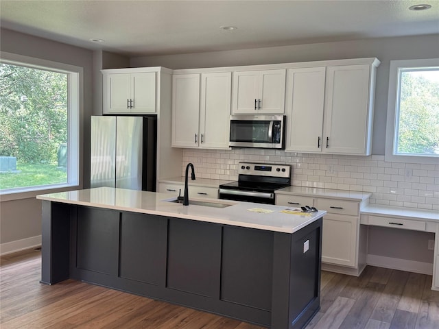 10009 Powell Ave, Johnston, IA 50131 - kitchen with appliances with stainless steel finishes, decorative backsplash, white cabinetry, light countertops, and wood finished floors