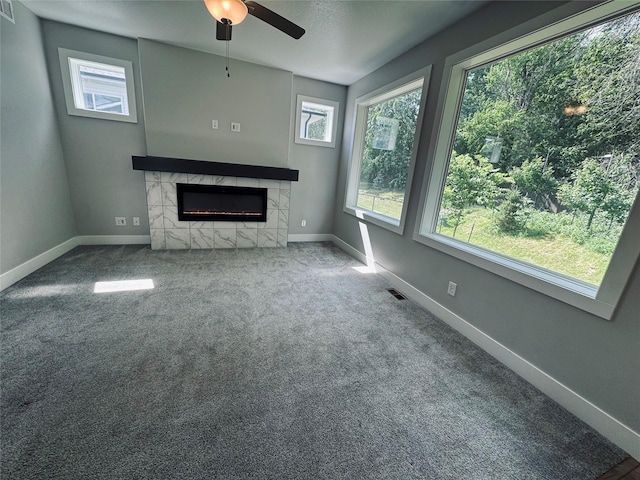 10009 Powell Ave, Johnston, IA 50131 - unfurnished living room featuring ceiling fan, a tiled fireplace, and carpet