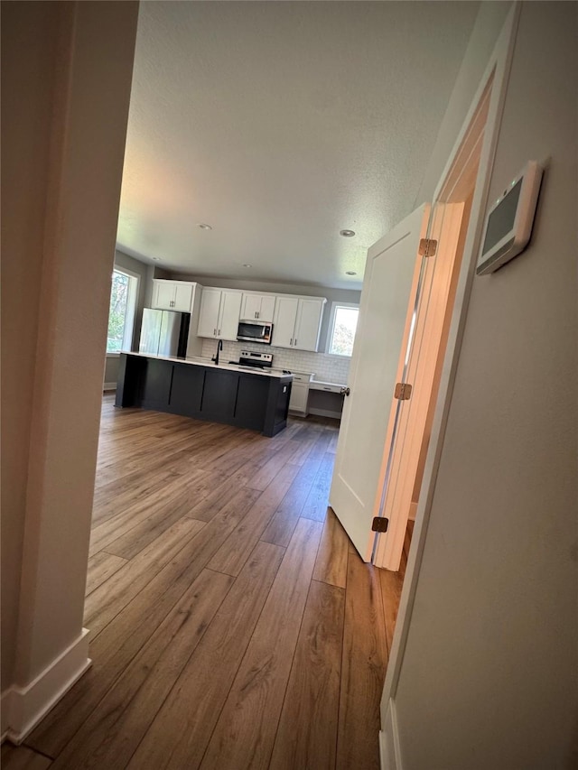 10009 Powell Ave, Johnston, IA 50131 - kitchen featuring appliances with stainless steel finishes, white cabinets, light countertops, dark wood-type flooring, and backsplash