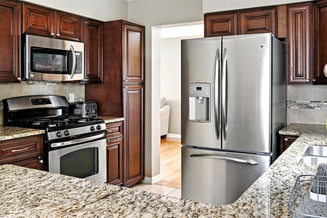 3832 Richmond Ave, Des Moines, IA 50317 - kitchen with stainless steel appliances, light stone counters, backsplash, and light tile patterned flooring