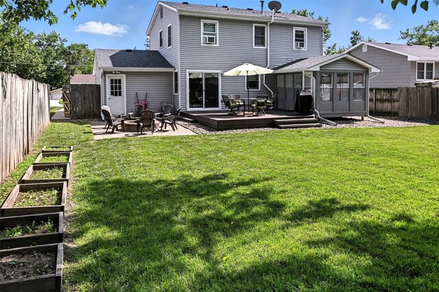 3832 Richmond Ave, Des Moines, IA 50317 - rear view of house featuring a vegetable garden, a sunroom, a fenced backyard, a fire pit, and a wooden deck