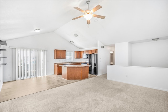 900 34th St SW, Bondurant, IA 50035 - kitchen with open floor plan, freestanding refrigerator, a ceiling fan, a kitchen island, and brown cabinets