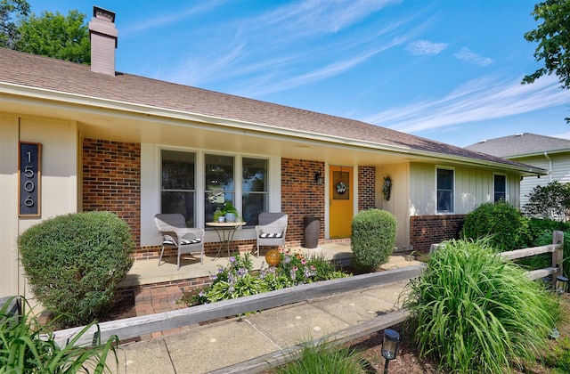 1506 S 14th St, Adel, IA 50003 - view of front facade featuring brick siding, a porch, a chimney, and roof with shingles