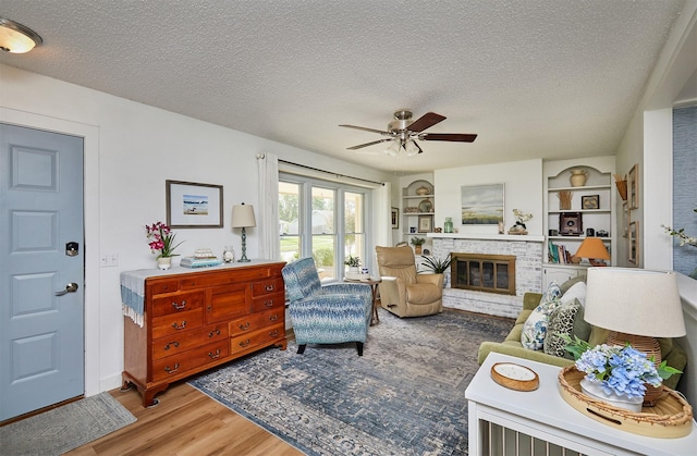 1506 S 14th St, Adel, IA 50003 - living room with a ceiling fan, wood finished floors, a textured ceiling, a fireplace, and built in features