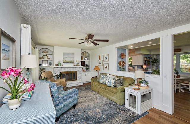 1506 S 14th St, Adel, IA 50003 - living area featuring wood finished floors, ceiling fan, a brick fireplace, and a textured ceiling