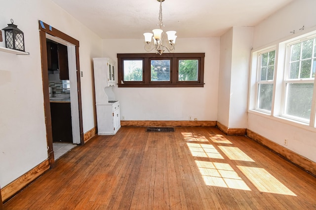 603 W Church St, Marshalltown, IA 50158 - unfurnished room featuring hardwood / wood-style flooring, a chandelier, and plenty of natural light