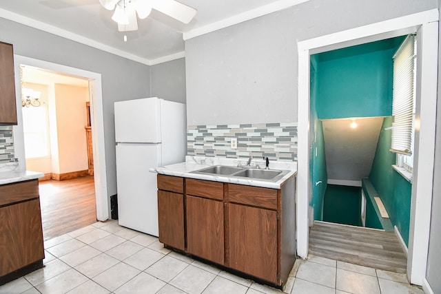 603 W Church St, Marshalltown, IA 50158 - kitchen featuring freestanding refrigerator, light tile patterned flooring, light countertops, decorative backsplash, and crown molding