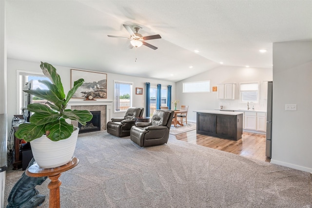 2708 NW Boulder Point Pl, Ankeny, IA 50023 - living area with light colored carpet, ceiling fan, vaulted ceiling, a tile fireplace, and light wood-type flooring